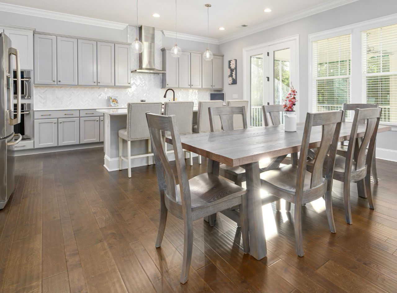 Spacious luxury kitchen with white cabinetry, wood tile flooring and large central island.